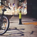 Bicycle parked on a quiet city street at night with blurred lights in the background