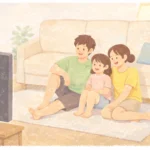 A barefoot family sitting on the living room floor, leaning against a sofa while casually watching TV together at home.