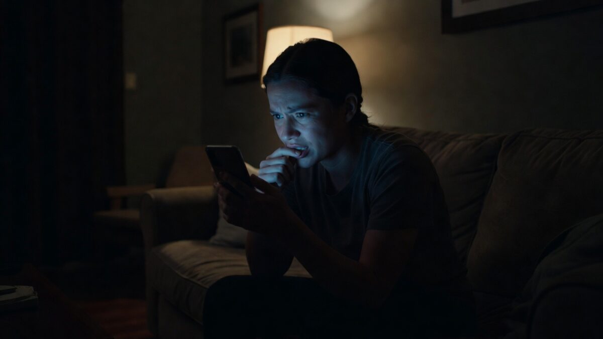 A person biting their nails while staring at a phone screen waiting for an important message